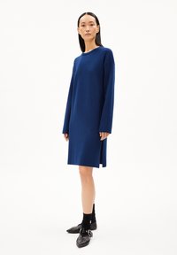 Abito lungo blu navy con maniche lunghe, dal fit morbido, realizzato in tessuto a maglia. Presenta spacchi laterali, scollatura rotonda ed è di lunghezza al ginocchio.