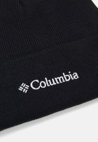 Μαύρο πλεκτό σκουφάκι με ραβδωτή υφή. Διαθέτει λευκό κεντητό λογότυπο "Columbia" στο μπροστινό μέρος. Απλός σχεδιασμός, χωρίς επιπλέον μοτίβα ή αξεσουάρ.