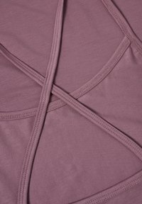 Tissu mauve à la texture lisse avec des bretelles croisées et des détails de couture précis, présentant un design ajusté et minimaliste.