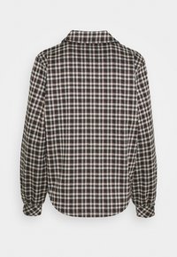 Camicia abbottonata con motivo a quadri in bianco e nero. Presenta un colletto, maniche lunghe e un orlo arrotondato. Realizzata in tessuto morbido.