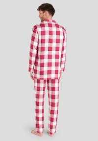 Conjunto de pijama a cuadros rojos y blancos, que incluye una camisa de manga larga y pantalones a juego, con una textura de tela suave y un diseño de cuello sencillo.