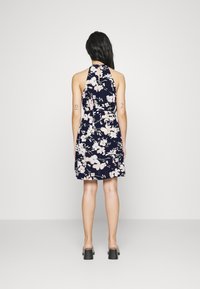 Granatowa, kwiecista sukienka na halter z dopasowanym gorsetem i rozkloszowanym dołem. Posiada miękką tkaninę, jasnoróżowe kwiaty oraz otwarty tył.