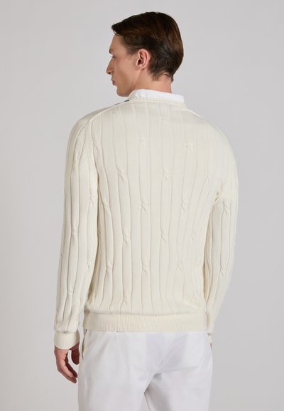 Maglione lavorato a maglia color crema con una texture a coste verticali e sottili dettagli a treccia. Presenta una scollatura tonda e polsini e orlo a coste.