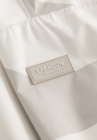 Lättviktig tyg i vitt med beige accenter. Har en texturerad etikett med "LARKSON HAMBURG" präglad, som beskriver en modern design.