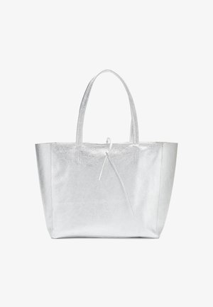 Srebrna metaliczna torba typu tote z dwoma uchwytami i ozdobnym wiązaniem z przodu, pokazana na białym tle.