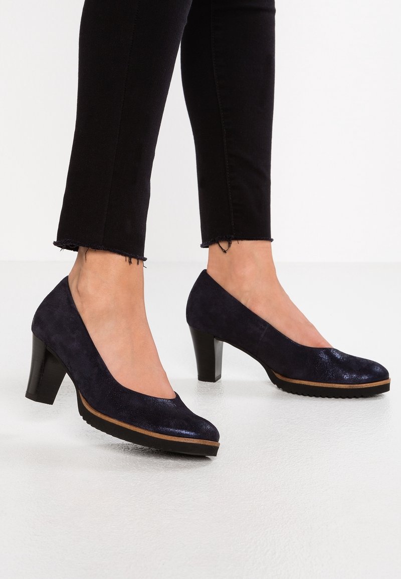 Chaussures à talons hauts en daim bleu marine foncé avec un embout brillant, un design arrondi et une semelle extérieure texturée. Le talon bloc noir est de hauteur modérée.