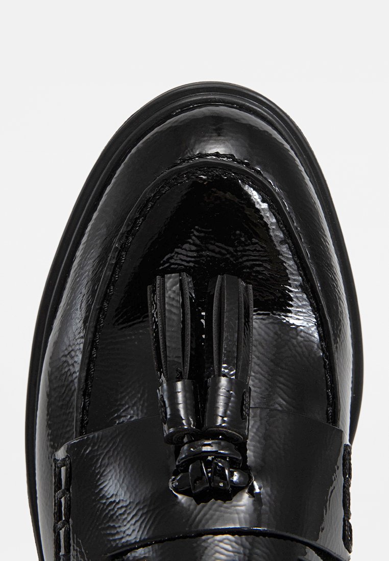 Schwarze Lackleder-Slipper mit glatter Oberfläche, dekorativen Fransen und einem runden Zehenentwurf. Gestickte Details an den Seiten.