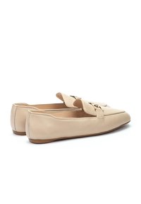 Mocasines de piel beige con punta redondeada, que cuentan con una correa decorativa y herrajes en tono dorado, además de una suela de goma plana.
