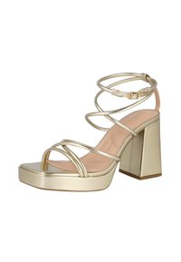 Sandalia de tacón alto dorada con correas, tacón bloque, correa en el tobillo con hebilla y plataforma de punta cuadrada sobre fondo blanco.