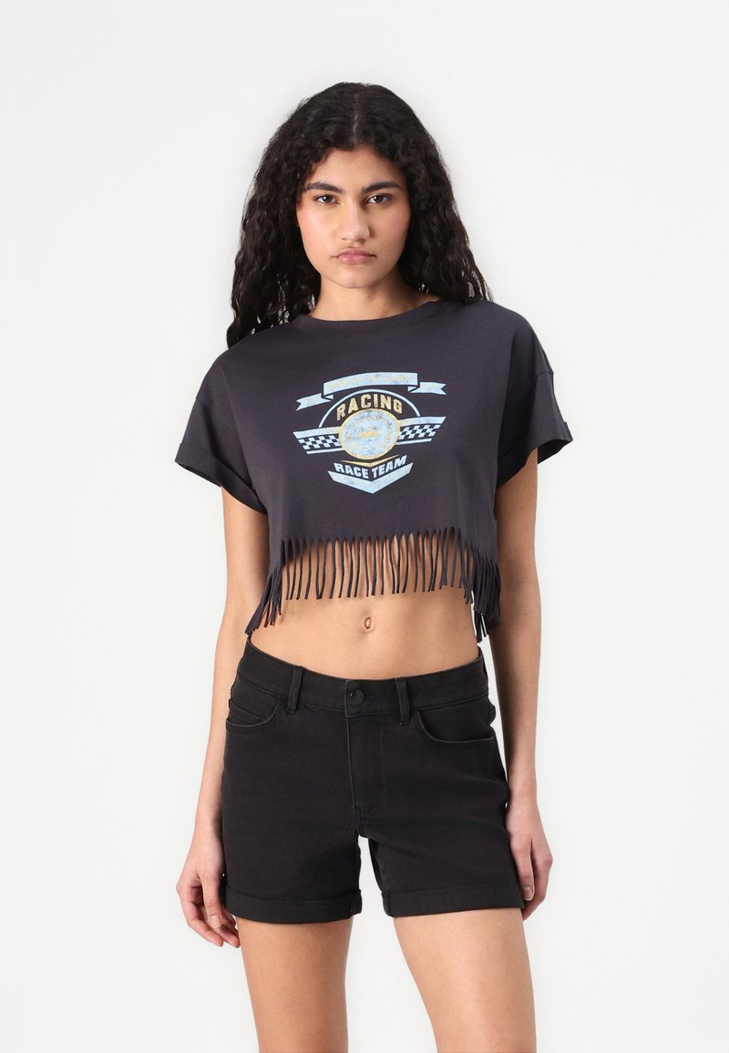 Black cropped t-shirt with fringe hem. Features a racing graphic on the front, light blue and white accents against a dark background.