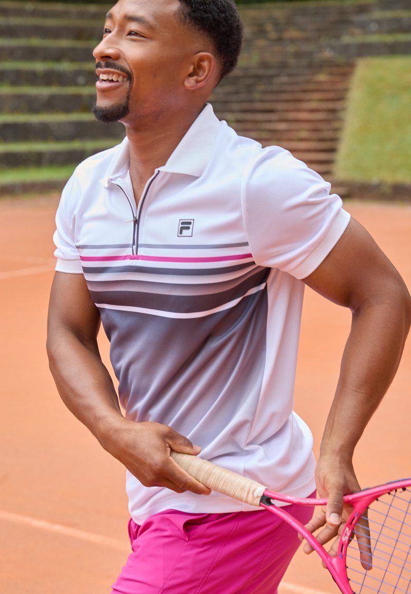 White polo shirt with gray and pink striped pattern, short sleeves, and collar; paired with bright pink shorts and a pink tennis racket.