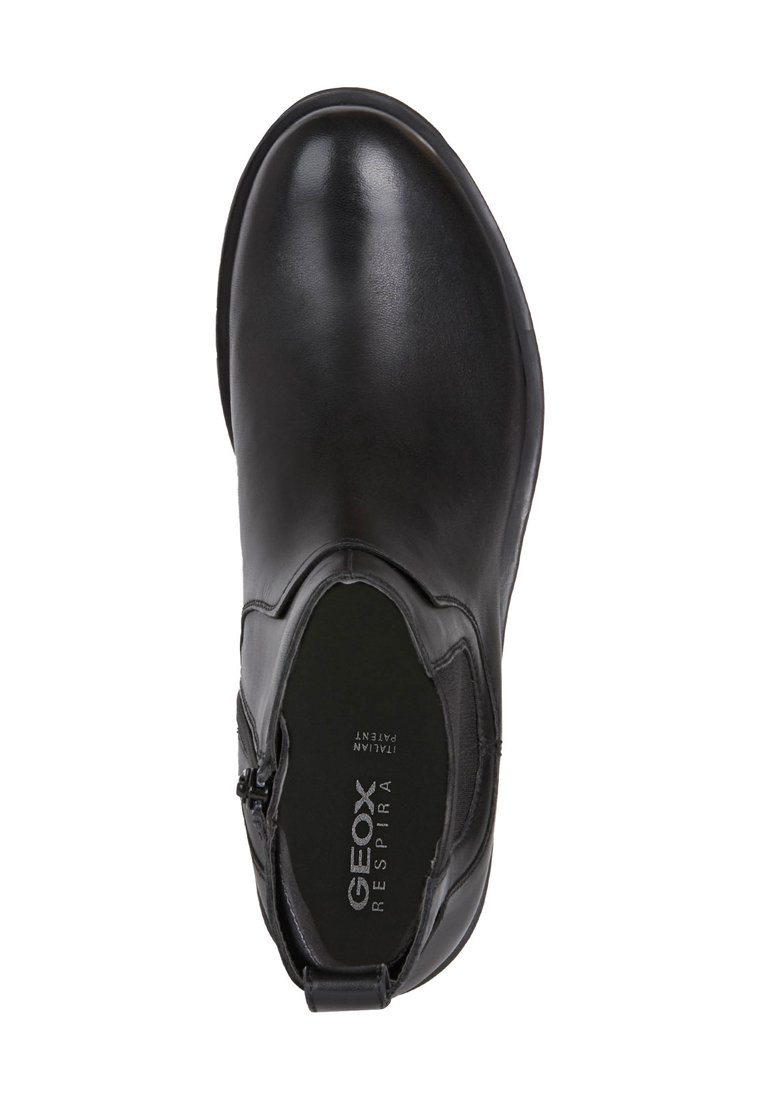 Botín de cuero negro hasta el tobillo con puntera redondeada, cremallera lateral y un sutil logotipo en la plantilla. Textura suave y diseño minimalista.