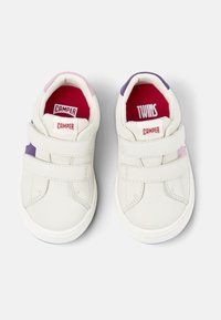 Chaussures en cuir blanches avec des bandes Velcro, accents violets et roses, et semelles intérieures rouges portant les inscriptions "TWINS" et "CAMPER". Bout arrondi et semelle en caoutchouc.