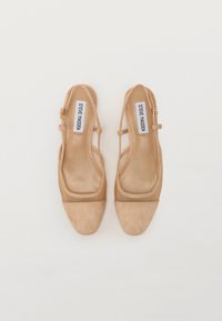Beige slingback-kengät, joissa on neliskulmainen kärki, nubukkinahkainen rakenne ja verkko-yksityiskohtia. Säädettävä hihna kullanvärisillä yksityiskohdilla.