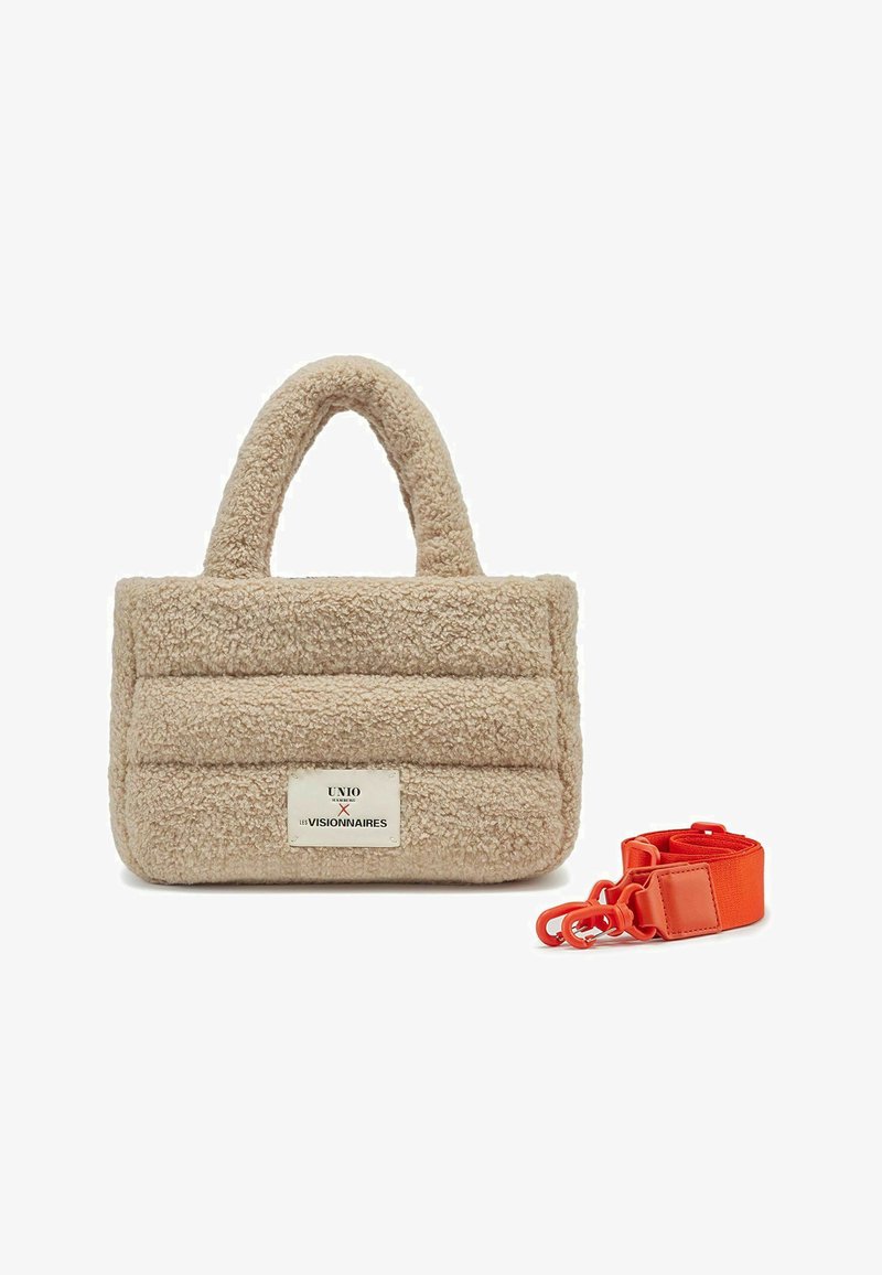 Bolso de mano de felpa beige con superficie texturizada, que presenta una etiqueta en la parte frontal y una correa ajustable de color naranja. Dos asas redondeadas en la parte superior.