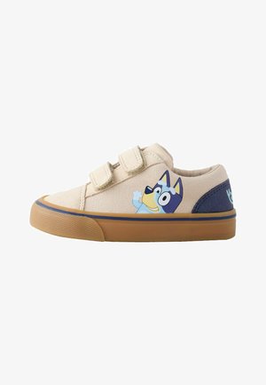 Chaussures en toile beige avec un dessin animé de chien bleu, double fermeture Velcro, accents bleu marine et semelle en caoutchouc gomme.