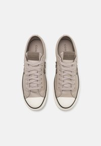 Beige leren sneakers met een ronde neus, vetersluiting, rubberen neuskap en een subtiel logodetail op de tong.