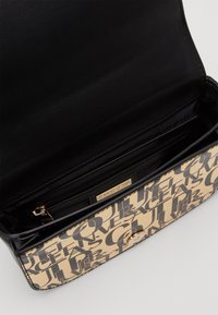 Borsa in finta pelle nera con un esterno beige che presenta grande testo nero. Dispone di una tasca con zip e una chiusura a scatto in tonalità oro.