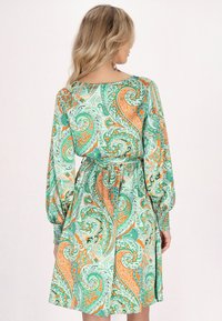 Grünes Kleid mit Paisley-Muster und orangefarbenen Akzenten, ausgestattet mit langen Puffärmeln, einer taillierten Taille und einer knie-langen A-Linien-Silhouette.