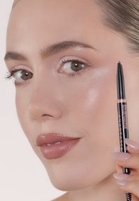 Oogpotlood met een ontwerp met zwarte schacht, fijne punt en een dubbele spoolie aan beide uiteinden. Zachte textuur met een donkere kleur. Model heeft een natuurlijke make-uplook.