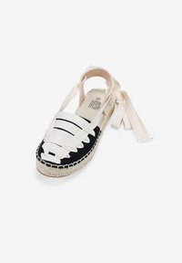 Espadrilles en blanco y negro con tiras de tela trenzada, punta redonda y suela de yute trenzado. Cuenta con lazos de cinta para un ajuste seguro. Talla 36.