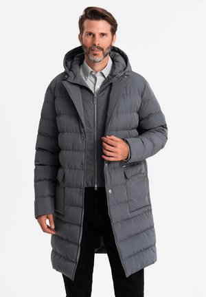 Abrigo acolchado gris con capucha, con acolchado horizontal, cierre de cremallera y bolsillos laterales. La tela es suave con un acabado mate.