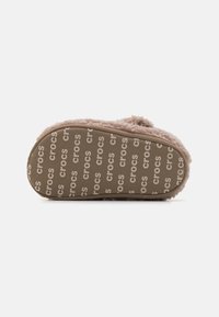Crocs suss, mille pehmea ja karvane ülemine osa helesinisena, tekstureeritud sisemus ja vastupidav kummist välispõhi, millel on kirjas "crocs."