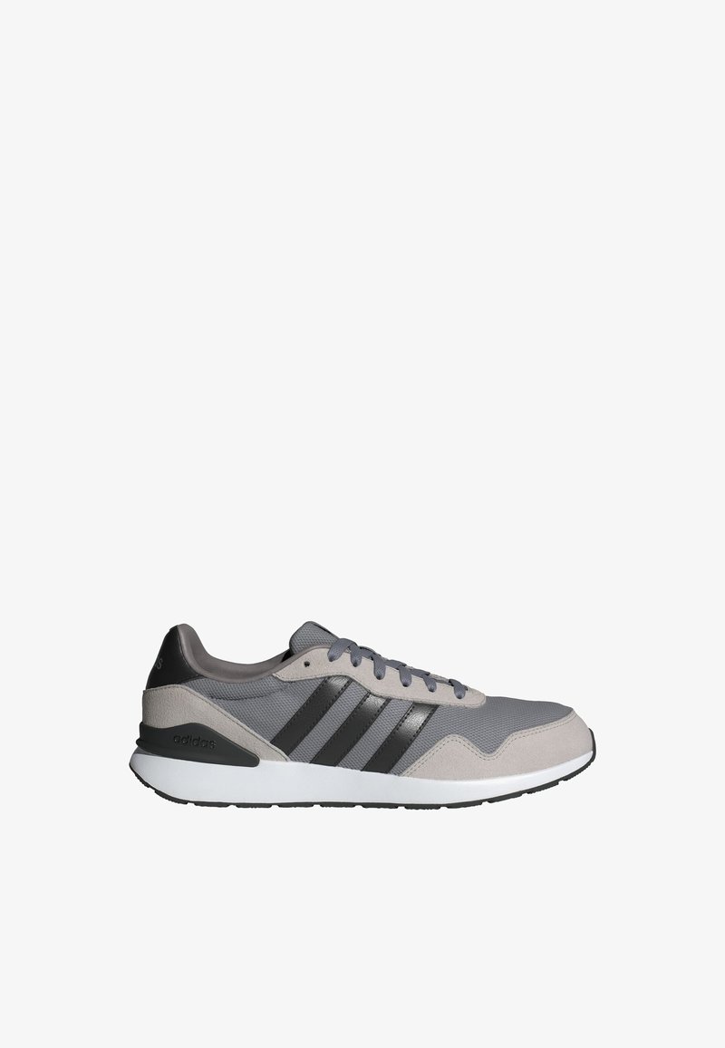 Baskets Adidas gris et noires avec une tige en mesh et en daim, une semelle blanche et trois rayures noires sur le côté.
