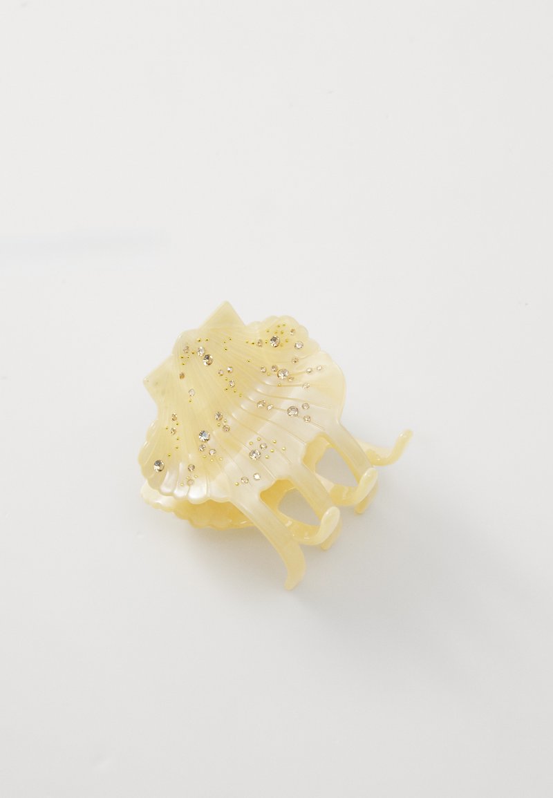 Clips de cabelo amarelo em forma de concha, com ribanhas onduladas e pequenas decorações cintilantes na sua superfície. Material plástico liso.
