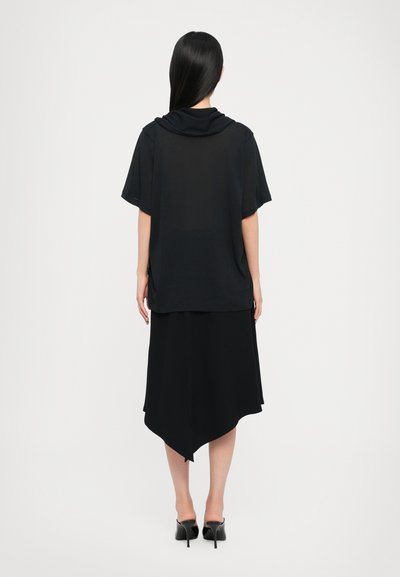 Outfit nero composto da una blusa corta e ampia con collo a drappeggio e una gonna lunga e asimmetrica. Tessuto morbido e design minimalista.