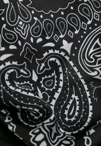 Tejido negro con un patrón de paisley blanco que presenta formas intrincadas, remolinos y acentos de puntos. Textura suave, material ligero.