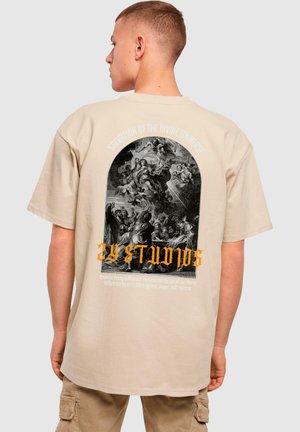 Beige oversized t-shirt featuring a large black and white graphic print on the back, text in orange and white above and below the image.