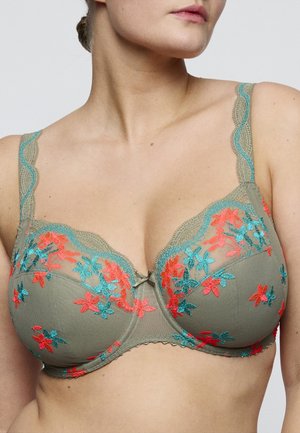 Vrouw draagt een olijfgroene beha met koraal- en turquoise bloemrijke borduursels en een kanten rand met geschulpte rand.