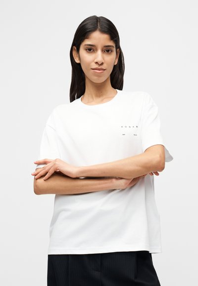 Άσπρο βαμβακερό t-shirt με στρογγυλή λαιμόκοψη, κοντά μανίκια και τυπωμένα λογότυπα στην αριστερή πλευρά. Μαλακή υφή και άνετη εφαρμογή.