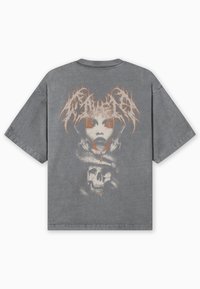 T-shirt cinzenta oversize com um grande gráfico nas costas de um rosto, cobra e caveira com detalhes em laranja. Textura suave do tecido.