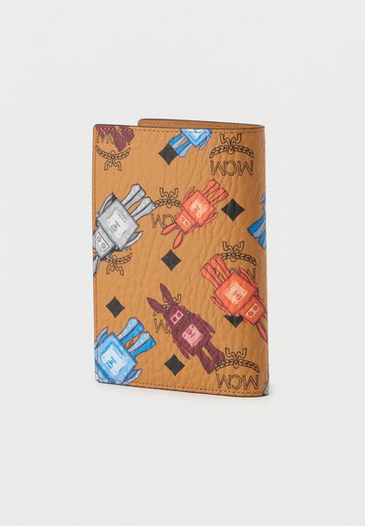 Καφέ κοντοράφικο πορτοφόλι με πολύχρωμους καρτούν χαρακτήρες σε μπλε, κόκκινο και λευκό, με μαύρα διαμαντένια σχέδια και το λογότυπο "MCM".