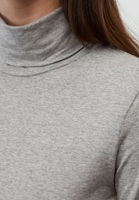 Hellgrauer Rollkragenpullover aus weichem, strukturiertem Stoff, mit hohem Kragen und minimalen Nähten für ein glattes Erscheinungsbild.