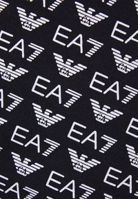 Svart textil med upprepade vita EA7-logotyper och vinge-emblem, som skapar ett djärvt mönster med en slät textur.