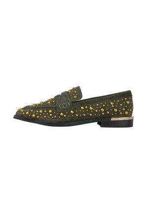 Mocasín de ante verde oscuro con tachuelas redondas doradas en toda su superficie, suela negra y pequeño tacón con ribete dorado.