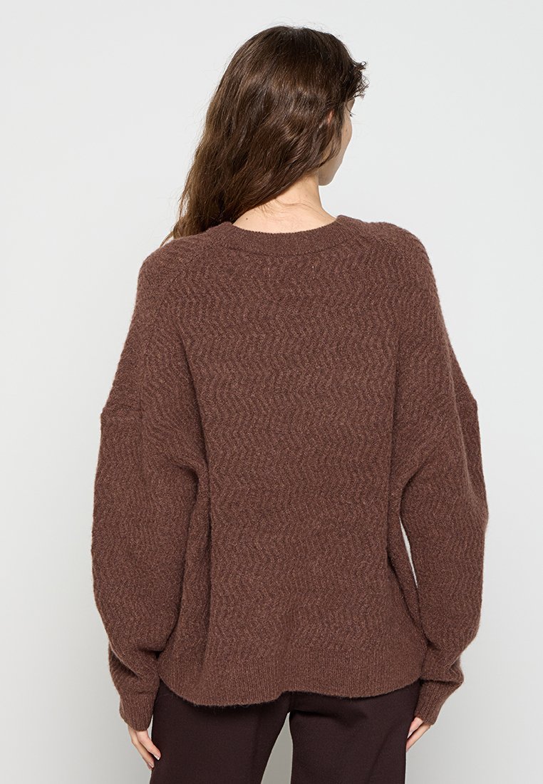 Brauner, übergroßer Pullover mit strukturiertem Fischgrätmuster, rundem Halsausschnitt und überschnittenen Schultern. Weiches, gestricktes Material mit langen Ärmeln.
