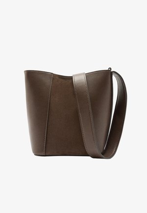 Brązowa skórzana torba na ramię o miękkiej fakturze, ustrukturyzowanym kształcie i szerokim pasku na ramię. Charakteryzuje się minimalistycznym designem i zaokrąglonymi krawędziami.