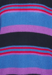 Randig stickad tröja med blå, rosa och svarta ränder samt röda accenter; textilstruktur, enhetligt mönster över ytan.