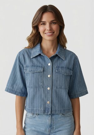 Mujer sonriendo con chaqueta vaquera de manga corta, abotonada, con rayas verticales y bolsillos delanteros con solapa, combinada con vaqueros azul claro.