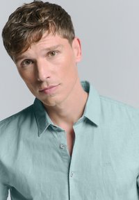 Lichtblauwe button-up shirt van textiel met een opgevouwen kraag en een klein geborduurd logo aan de linkerkant.