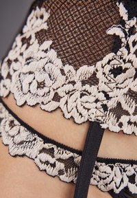 Sort blonde lingerie med detaljeret beige blomsterbroderi, blød tekstur og justerbare stropper. Detaljeret design med kontrasterende farver.