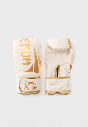 Coppia di guantoni da boxe bianchi e dorati con il marchio "Venum" e la scritta "Adrenaline Inside" sulle cinghie del polso, mostrati da lato frontale e dal palmo.