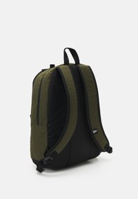 Black and olive green backpack with padded sides, adjustable straps, top handle, and a side pocket for storage. Smooth fabric texture.