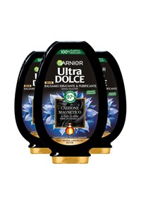 Tre bottiglie nere di balsamo Garnier Ultra Dolce con design floreale blu, dettagli dorati e un'etichetta che indica il 97% di ingredienti naturali.