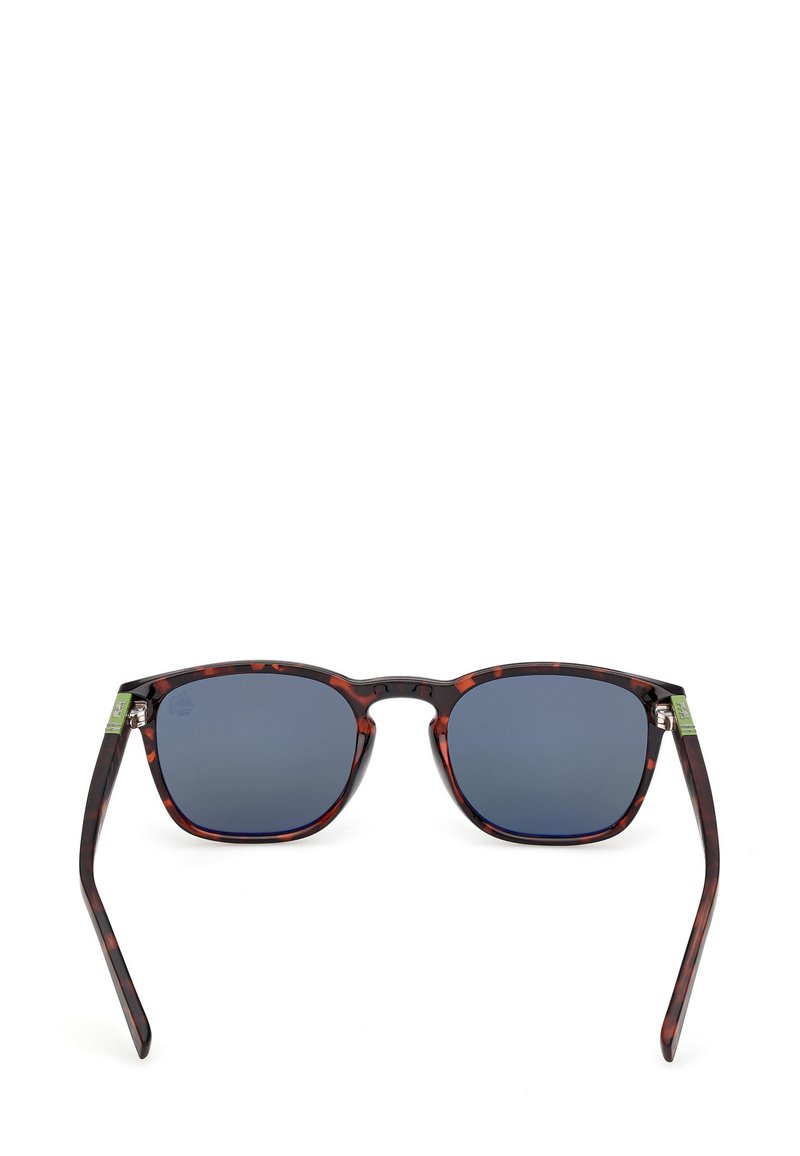 Lunettes de soleil à motif écaille de tortue avec des montures carrées, des verres foncés et des branches fines. Présente un accent vert subtil sur la branche gauche.