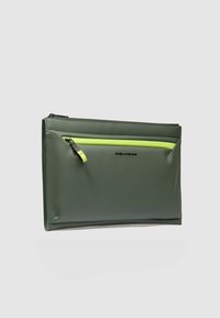 Bolsa impermeable verde con textura suave, que cuenta con un bolsillo con cremallera de color verde brillante contrastante y un logo de la marca en la parte delantera.